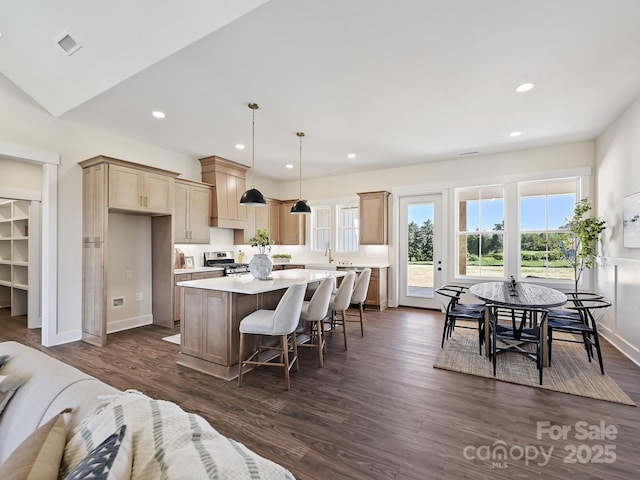 kitchen featuring dark wood-style floors, light countertops, a breakfast bar, a kitchen island, and gas range