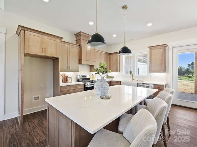 kitchen featuring dark wood-style flooring, a center island, backsplash, appliances with stainless steel finishes, and recessed lighting