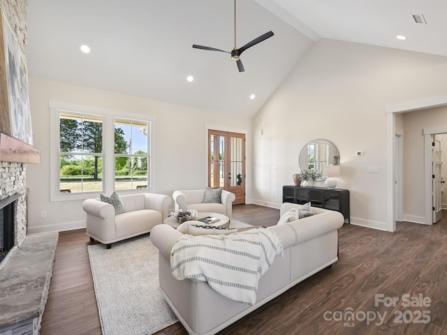 living area featuring a stone fireplace, a wealth of natural light, a ceiling fan, and high vaulted ceiling