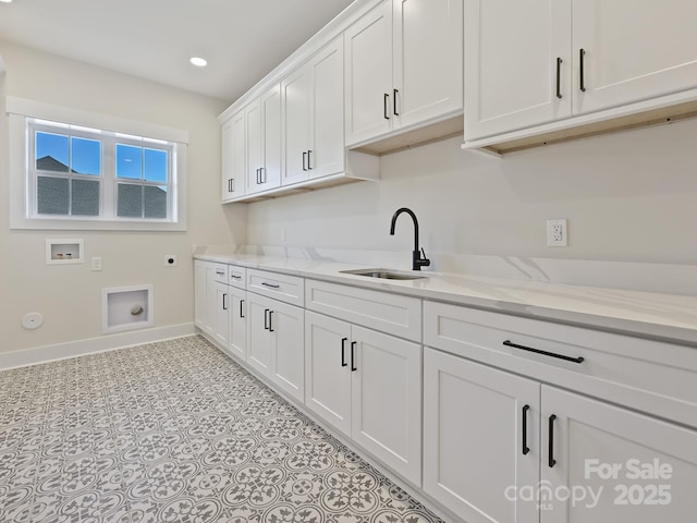 laundry room featuring a sink, baseboards, electric dryer hookup, cabinet space, and washer hookup