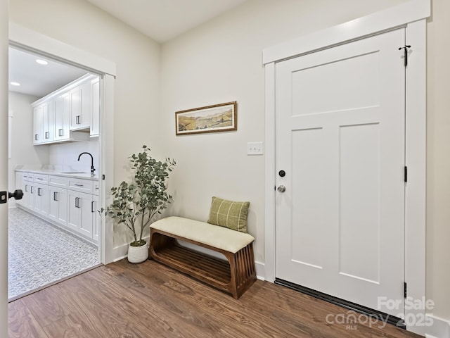 doorway to outside with baseboards, wood finished floors, a sink, and recessed lighting