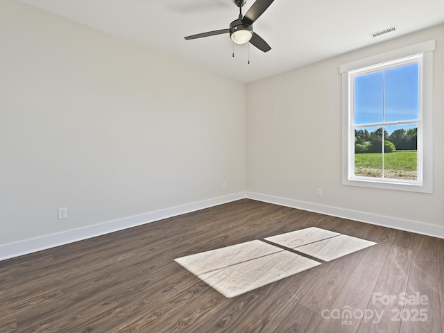 empty room with baseboards, a ceiling fan, visible vents, and dark wood-style floors