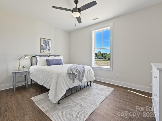 bedroom with baseboards, a ceiling fan, wood finished floors, and visible vents
