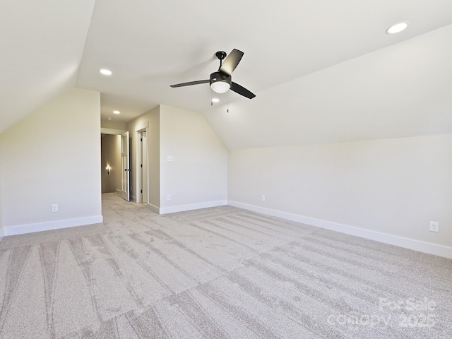 additional living space featuring light colored carpet, vaulted ceiling, a ceiling fan, and baseboards