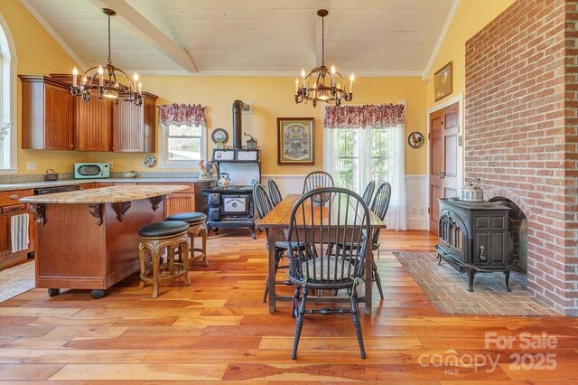 dining area with an inviting chandelier, a wealth of natural light, and a wood stove