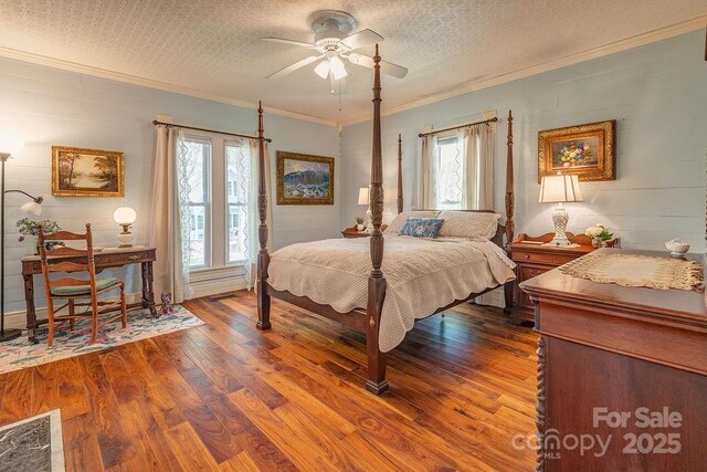 bedroom with dark wood-style flooring, ceiling fan, ornamental molding, and a textured ceiling