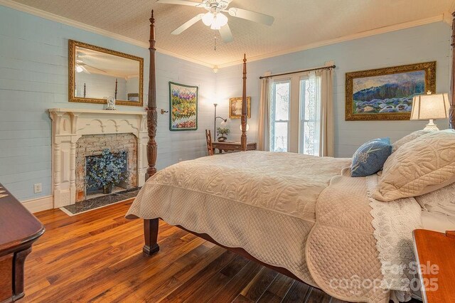 bedroom featuring crown molding, a ceiling fan, a brick fireplace, and hardwood / wood-style flooring