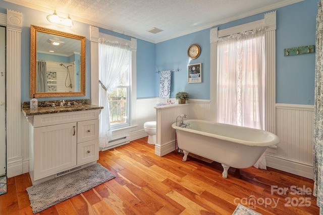 bathroom with hardwood / wood-style floors, visible vents, crown molding, and wainscoting