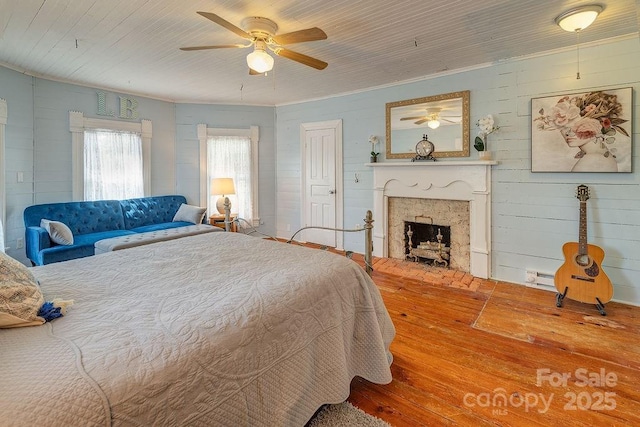 bedroom with a ceiling fan, hardwood / wood-style floors, and a fireplace
