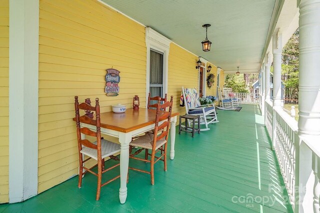 wooden deck featuring a porch and outdoor dining area