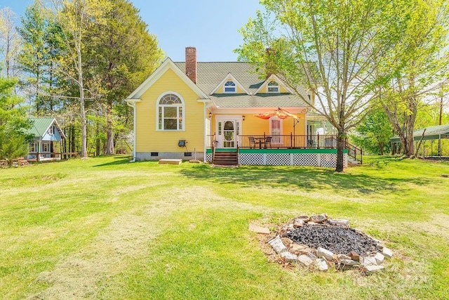 rear view of house with a deck, an outdoor fire pit, a yard, and a chimney