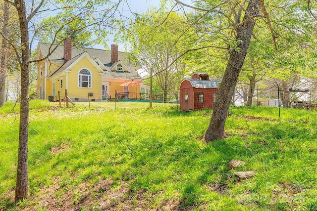view of yard featuring fence, a shed, and an outbuilding