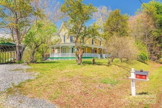 victorian-style house featuring a porch, a carport, and a front yard