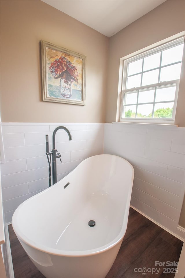 8810 Cool Meadow Dr, Huntersville, NC 28078 - bathroom featuring tile walls, wood finished floors, a freestanding bath, wainscoting, and a sink