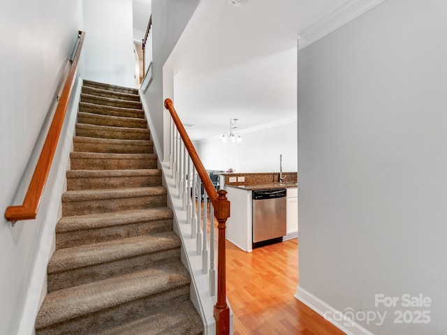 stairway with a chandelier, baseboards, crown molding, and wood finished floors