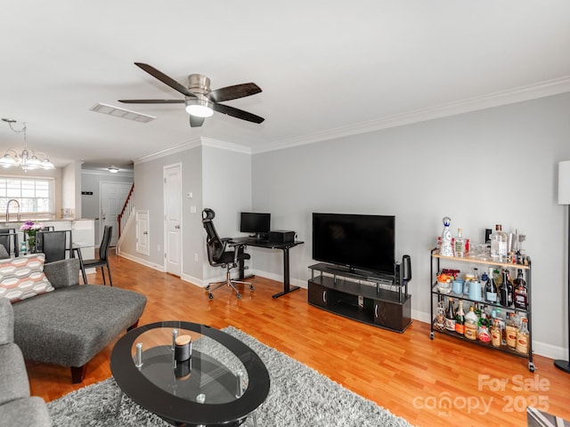 living area featuring crown molding, wood finished floors, ceiling fan, and stairs