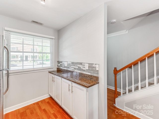 kitchen featuring light wood finished floors, visible vents, freestanding refrigerator, and backsplash