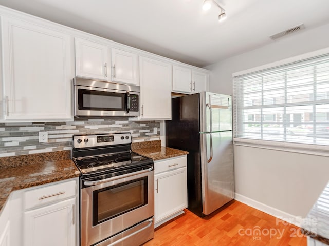 kitchen with tasteful backsplash, white cabinetry, light wood-style floors, visible vents, and stainless steel appliances