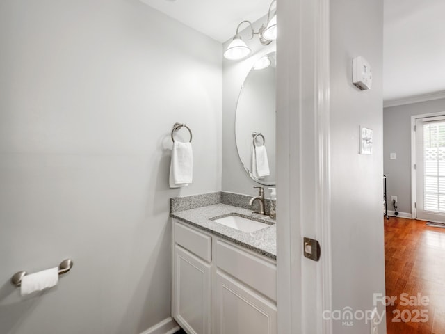 bathroom featuring vanity, baseboards, ornamental molding, and wood finished floors