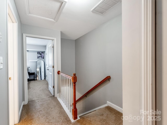 hallway featuring attic access, visible vents, an upstairs landing, and carpet floors