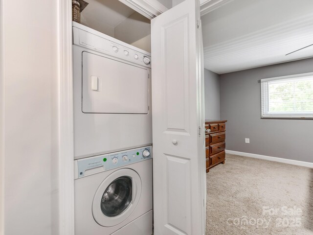 clothes washing area with stacked washer / dryer, laundry area, baseboards, and carpet floors