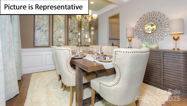 dining room featuring a decorative wall, a notable chandelier, and wood finished floors