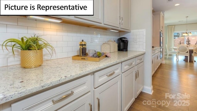 kitchen with recessed lighting, light wood-style flooring, light stone countertops, decorative light fixtures, and decorative backsplash