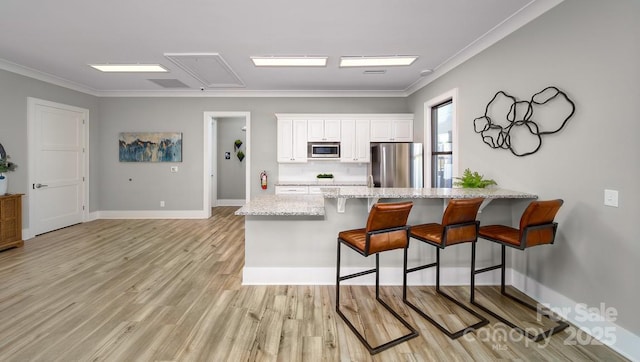 kitchen with white cabinets, a peninsula, a breakfast bar area, stainless steel appliances, and light stone counters