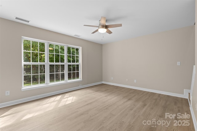 unfurnished room featuring baseboards, a ceiling fan, wood finished floors, and visible vents