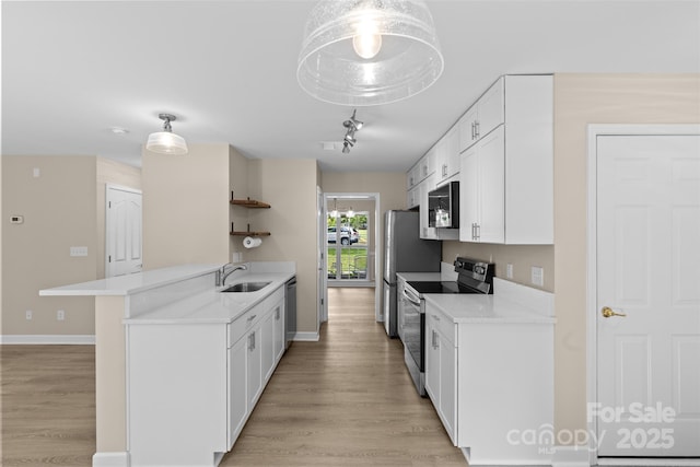 kitchen with light countertops, appliances with stainless steel finishes, a sink, and light wood-style flooring