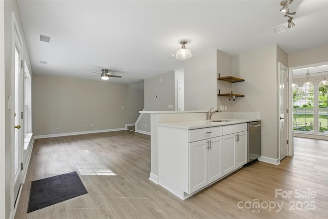 kitchen featuring open shelves, stainless steel dishwasher, light wood-style flooring, and visible vents