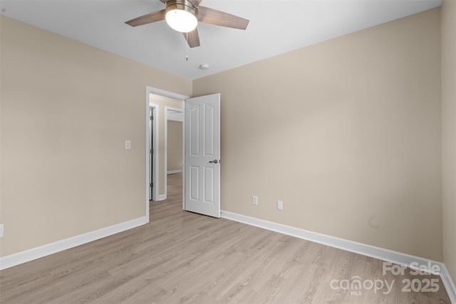 empty room with baseboards, a ceiling fan, and light wood finished floors