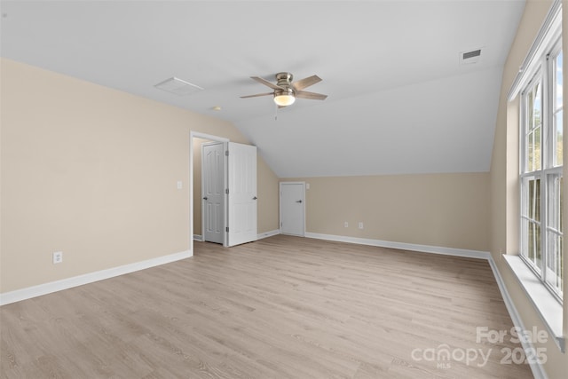 additional living space featuring light wood-style floors, a ceiling fan, baseboards, lofted ceiling, and visible vents