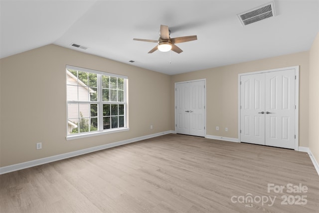 unfurnished bedroom featuring two closets, light wood-style flooring, and visible vents
