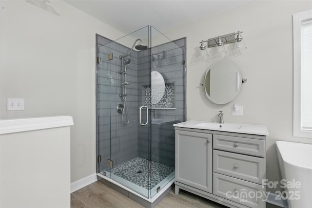 full bathroom with vanity, a shower stall, and wood finished floors