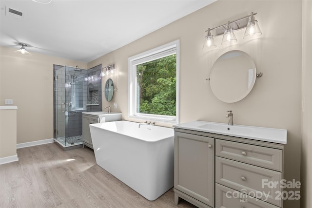 bathroom featuring vanity, a stall shower, wood finished floors, and visible vents