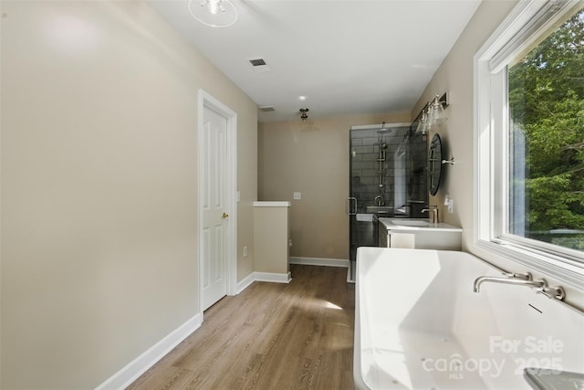 bathroom featuring a freestanding tub, a stall shower, wood finished floors, and a wealth of natural light
