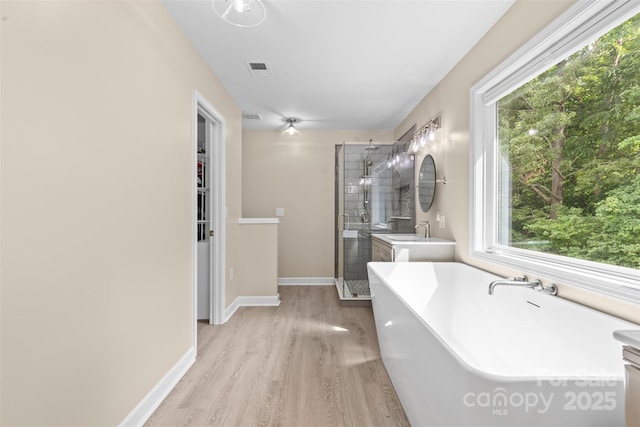 full bathroom featuring a sink, baseboards, a freestanding tub, wood finished floors, and a stall shower