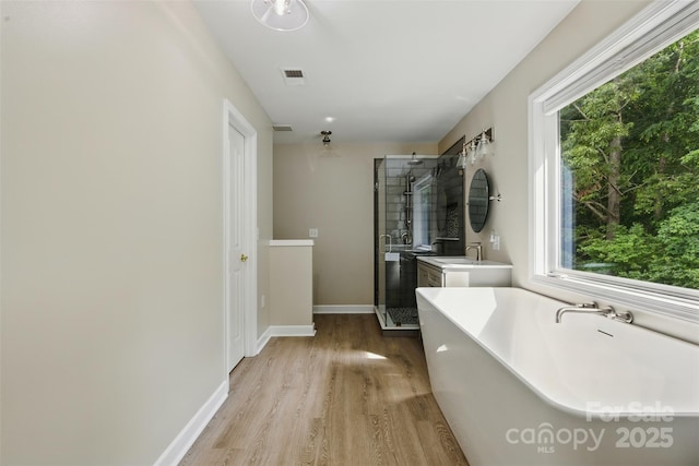 full bath with a stall shower, wood finished floors, a wealth of natural light, and a soaking tub