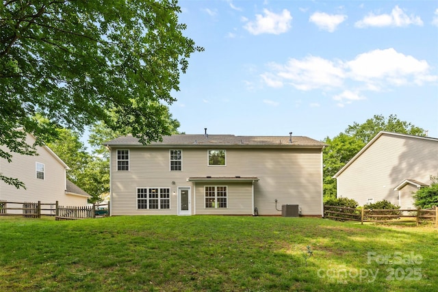 rear view of house featuring a lawn, central AC, and a fenced backyard