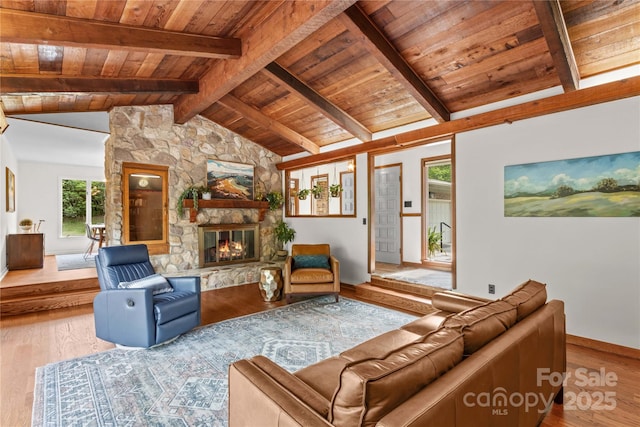 living area with wood ceiling, wood finished floors, lofted ceiling with beams, and a stone fireplace