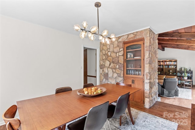 dining space featuring lofted ceiling, wood finished floors, and a notable chandelier