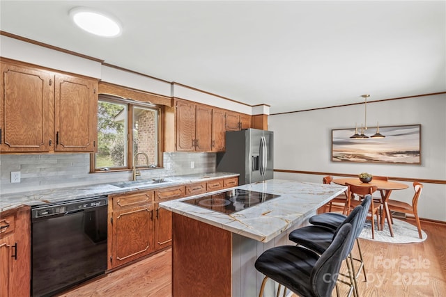 kitchen with black appliances, a kitchen island, light wood finished floors, and backsplash