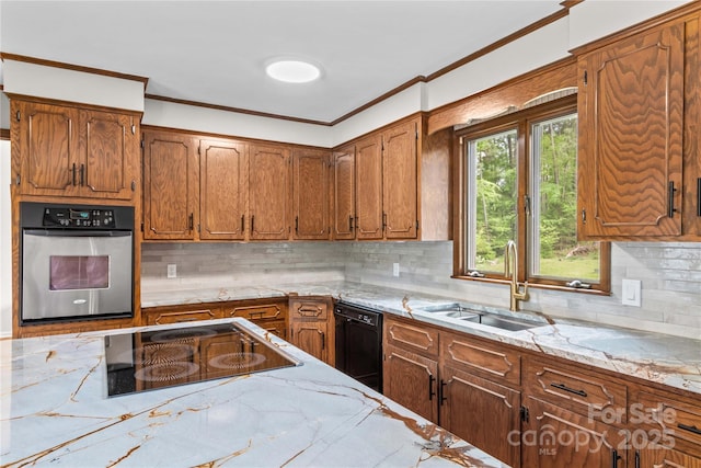 kitchen featuring brown cabinetry, black appliances, crown molding, and a sink
