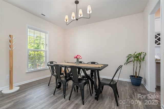 dining room with visible vents, baseboards, a chandelier, and wood finished floors