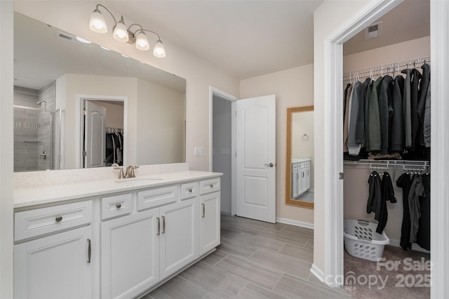 bathroom featuring a shower stall, vanity, a spacious closet, and visible vents