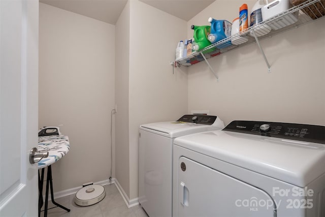 laundry room featuring laundry area, washing machine and clothes dryer, baseboards, and light tile patterned floors