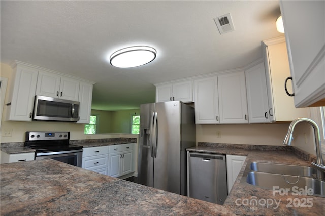 280 Fletcher View Dr, Fletcher, NC 28732 - kitchen featuring stainless steel appliances, a sink, white cabinets, dark countertops, and a peninsula