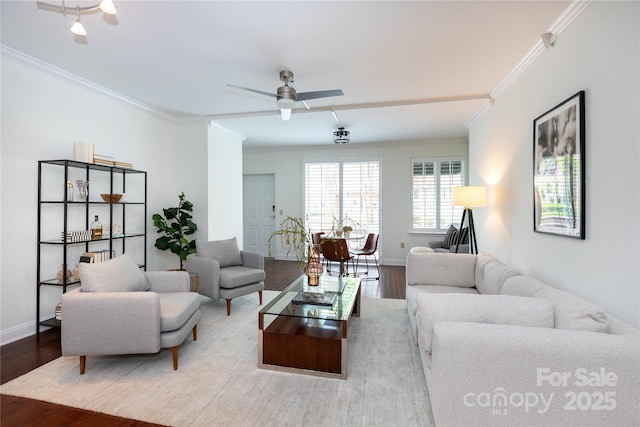 living room featuring baseboards, ornamental molding, a ceiling fan, and wood finished floors