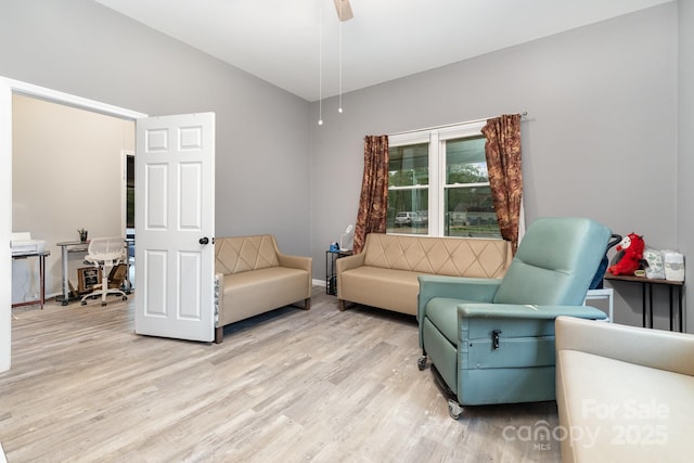 living room with ceiling fan, baseboards, light wood-style floors, and lofted ceiling